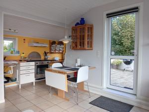 a kitchen with a table and chairs and a window at Strand Huset in Fåborg