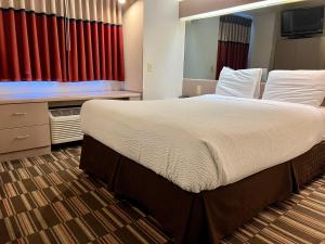 uma cama grande num quarto de hotel com cortinas vermelhas em Microtel Inn & Suites by Wyndham Bloomington MSP Airport em Bloomington