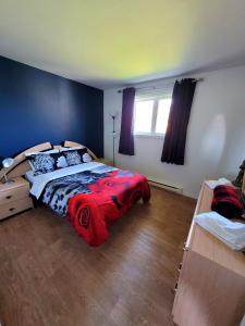 1 dormitorio con 1 cama con manta roja en Maison St-Raymond Duplex en Matane