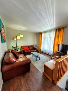 ein Wohnzimmer mit einem Ledersofa und einem TV in der Unterkunft Maison St-Raymond Duplex in Matane