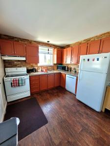 una cocina con electrodomésticos blancos y armarios de madera en Maison St-Raymond Duplex en Matane