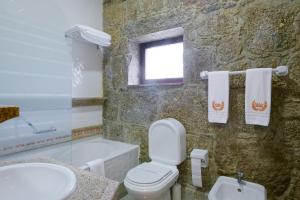 La salle de bains est pourvue de toilettes, d'un lavabo et d'une baignoire. dans l'établissement Hotel de Charme Quinta do Pinheiro, à Freamunde