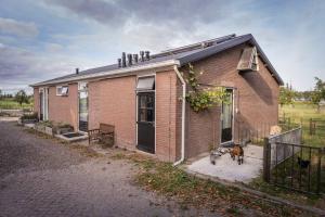una casa de ladrillo con dos perros parados fuera de ella en De Kaasmakerij - Ruim vakantiehuisje op Huize Blokland en Hem