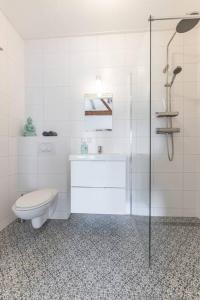 een witte badkamer met een toilet en een douche bij De Kaasmakerij - Ruim vakantiehuisje op Huize Blokland in Hem