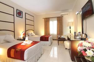 a hotel room with two beds and a television at Aliante Malang in Malang