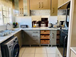 a kitchen with a sink and a washing machine at The Valley, tranquil 3 bedroom home with pool in Midrand