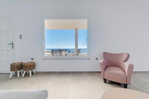 ein Wohnzimmer mit einem Stuhl und einem Fenster in der Unterkunft Captain View in Ano Syros
