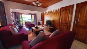 uma sala de estar com sofás vermelhos e uma televisão em Villa Milou em Baie Sainte Anne