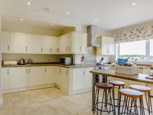 a kitchen with white cabinets and bar stools at Henrys Retreat in Ingoldsby