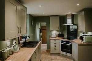 una cucina con pareti verdi e armadi bianchi di White Side Cottage a Haltwhistle