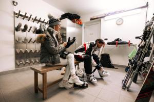two people sitting on a bench in a dressing room at Fogajard Lovely Chalet in Madonna di Campiglio