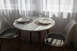 una mesa blanca con 2 sillas y 2 vasos en Przytulny, spokojny, wyposażony apartament, en Poznan