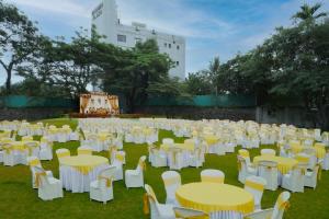 Hotel Bramha Inn في Dāpuri: مجموعة من الطاولات والكراسي البيضاء في الميدان