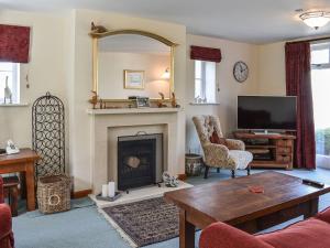 a living room with a fireplace and a tv at Myrtle Cottage in Puncknowle
