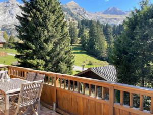 une terrasse en bois avec une table, des chaises et un arbre dans l'établissement PATURAGE Demi chalet 4 chambres, à La Clusaz