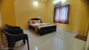 a bedroom with a bed and chairs and a window at Aadhya guest house in Tiruvannāmalai