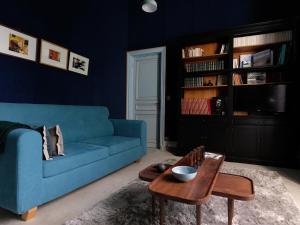 ein Wohnzimmer mit einem blauen Sofa und einem Tisch in der Unterkunft Mille et une feuilles in Saint-Martin-lez-Tatinghem
