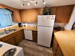 Una cocina con refrigerador blanco y gabinetes de madera. en Oasis #7 Coastal Escape in Daytona Beach Shores-Walk To The Beach, en Daytona Beach Shores