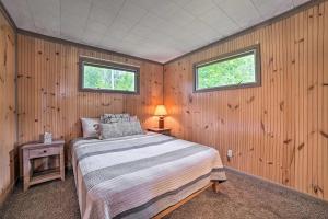 a bedroom with a bed and two windows at Comfy Burt Lake Abode - On-Site Lake Access! 