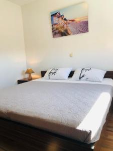 a bedroom with a white bed with a picture on the wall at Apartment MiaAntonia in Vrsi