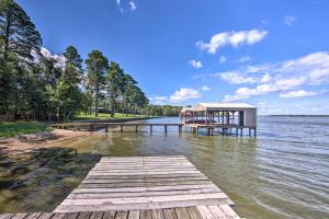 ein Dock mit einem Gebäude auf einem Wasserkörper in der Unterkunft Luxe Lakehouse with Sunset Views on Lake Palestine! in Flint