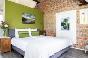een slaapkamer met een groot bed met een bakstenen muur bij Beerze Brouwerij Hotel in Vessem