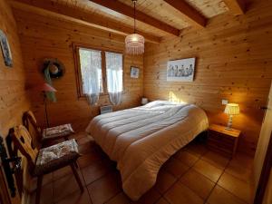 ein Schlafzimmer mit einem Bett in einer Holzhütte in der Unterkunft Murgiers B1 - Chalet mitoyen in La Clusaz