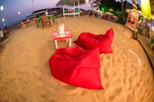 duas almofadas vermelhas na areia numa praia em International Beach Hotel & Restaurant em Hikkaduwa