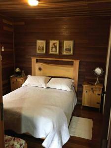 a bedroom with a large white bed with wooden walls at Casa de campo em Monte Verde , linda vista para montanhas in Monte Verde