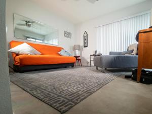 sala de estar con cama de color naranja y sofá en Desert Dream, en Palm Desert