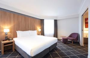 a hotel room with a bed and a chair at Furama Darling Harbour in Sydney