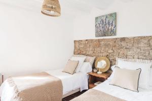 a bedroom with two beds and a stone wall at Menta Rural in San Pedro Sallavinera