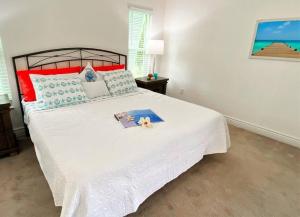 Un dormitorio con una cama blanca con un libro y una muñeca. en Just beachy Pool Gulf access, en Cabo Coral