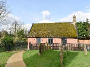 een oud bakstenen huis met een groen dak bij The Hay Barn in Barnby