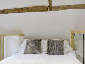 a white bed with two pillows on top of it at The Hay Barn in Barnby