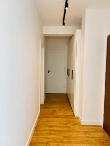 an empty hallway with a white door and a wooden floor at Nowe 3 pokojowe mieszkanie z dużym tarasem in Kalisz