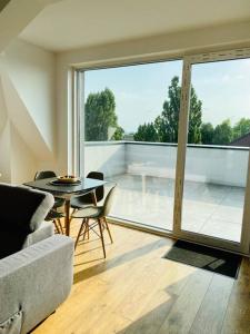 a living room with a table and chairs and a large window at Nowe 3 pokojowe mieszkanie z dużym tarasem in Kalisz