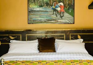 a bedroom with a bed with a painting on the wall at The Forest Resort - Lweza in Makindye