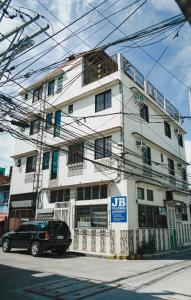 ein schwarzes Auto, das vor einem weißen Gebäude parkt in der Unterkunft JB Valdres Apartment in Manila