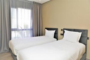 two white beds in a room with a window at Dominium Residence in Agadir