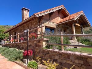 una casa de piedra con una valla y flores en Los Chozos de la Braña, en Brañosera