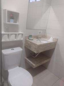 a white bathroom with a toilet and a sink at Cantinho da Sônia in Foz do Iguaçu