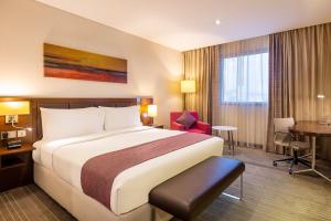 Pokój hotelowy z dużym łóżkiem i biurkiem w obiekcie Holiday Inn AlSeeb Muscat, an IHG Hotel w Maskacie