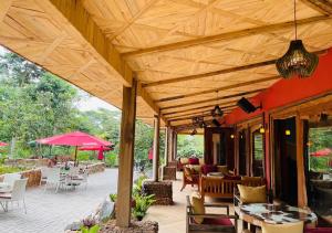 un patio con mesas y sillas bajo un techo de madera en The Forest Resort - Lweza en Makindye