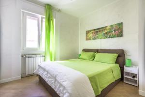 a bedroom with a bed with green sheets and a window at RomaDamare in Passoscuro