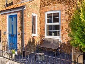 a brick house with a blue door and a bench at Elf Cottage in Heacham