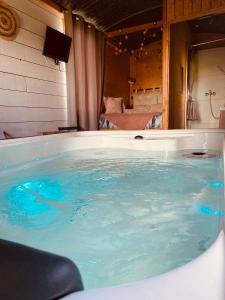 a large tub filled with blue water in a room at Chambre avec spa privé in Candor