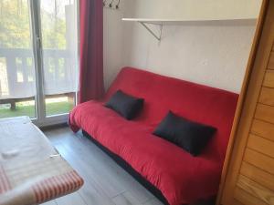 - un canapé rouge avec deux oreillers noirs dans l'établissement studio 4 pers Puy-Saint-Vincent 1700, à Puy-Saint-Vincent