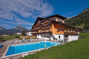 una casa con piscina frente a ella en Hotel Haus Michaela, en Sappada