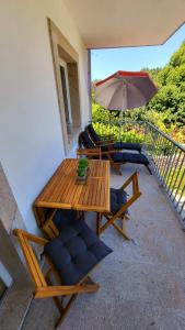 een patio met een tafel en stoelen en een parasol bij Casa Barca Velha in Ponte da Barca